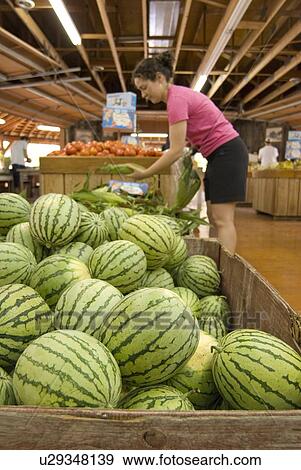 Stock Photo - A woman (20-25) chooses Fresh produce at a roadside fruit stand; Canada, British Columbia, Keremeos. Fotosearch