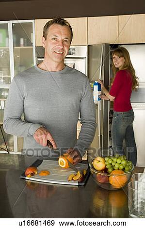 Stock Photo - Couple cutting organic fruit for smoothie, Winnipeg, Canada. Fotosearch