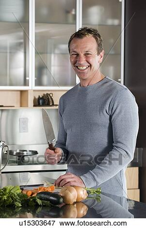 Stock Photo - Man with vegetables in kitchen, Winnipeg, Canada. Fotosearch