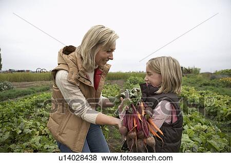 Stock Photo - Mother and daughter at an organic farm with fresh vegetables, Ladner, British Columbia, Canada. Fotosearch