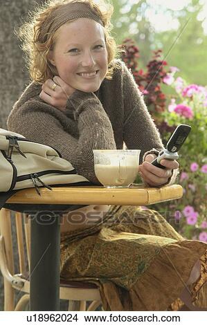 Smiling woman holds cell phone at outdoor restaurant, Wasagaming, Riding Mountain National Park, Manitoba, Canada View Large Photo Image Picture - Smiling woman holds cell phone at outdoor restaurant, Wasagaming, Riding Mountain National Park, Manitoba, Canada. Fotosearch