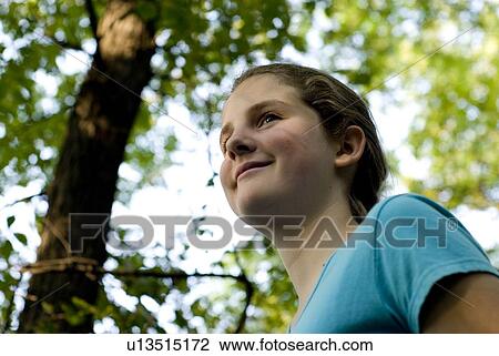 Stock Image - Twelve year old girl stands under crab apple tree, Winnipeg, Canada. Fotosearch