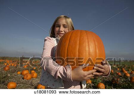 Stock Image - Young girl holding large organic pumpkin, Ladner, British Columbia, Canada. Fotosearch