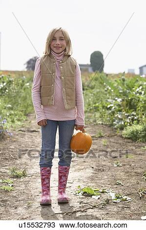 Young girl standing in field with organic pumpkin, Ladner, British Columbia View Large Photo Image Stock Image - Young girl standing in field with organic pumpkin, Ladner, British Columbia. Fotosearch