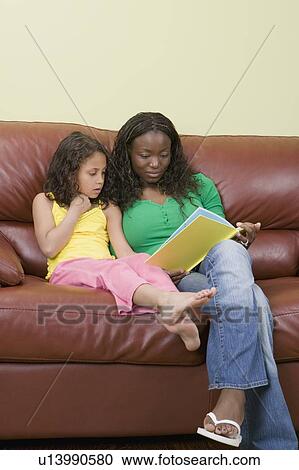 Stock Image - African American mom and Mulatto girl 6 years. Reading.. Fotosearch