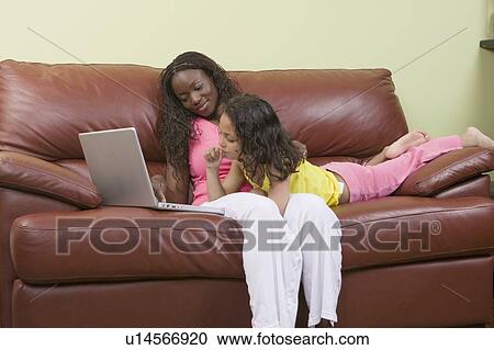Stock Image - African American mom and Mulatto girl 6 years. Working on laptop.. Fotosearch