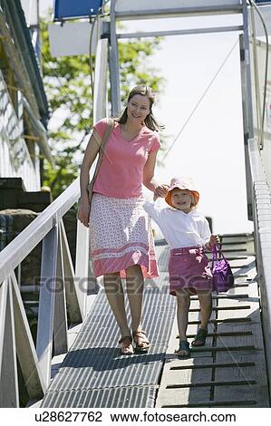Stock Image - Caucasian Mom and 4 year old Daughter, walking down a ramp to a boat dock, Granville Island, Vancouver, B. C.. Fotosearch