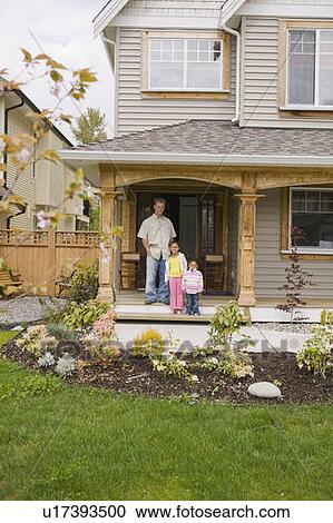 Stock Image - Caucasin dad and his two Mulatto daughters (3 and 6 years old) on the porch of their home. Abbotsford, BC.. Fotosearch