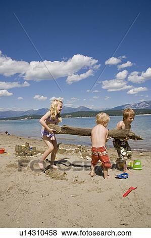 Stock Photo - Children playing on beach on Lake Koocanusa in the East Kootenays near Fernie, British Columbia, Canada. Fotosearch