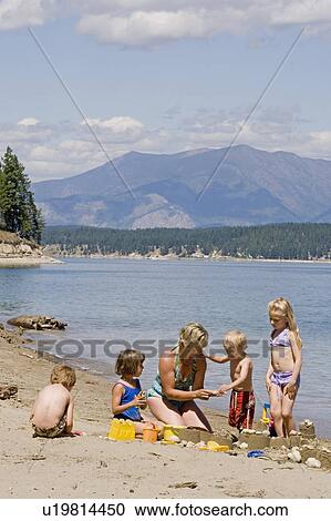 Stock Image - Children playing on beach with mom, on Lake Koocanusa in the East Kootenays near Fernie, British Columbia, Canada. Fotosearch