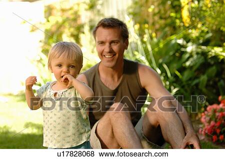 Stock Photo - Dad & baby in grass, Regina, Saskatchewan. Fotosearch