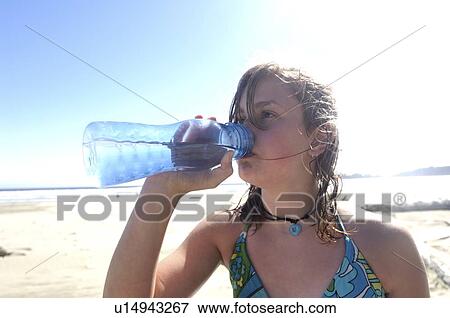 Stock Photo - Girl drinking clean water from refillable container, on beach, Vancouver Island, Canada. Fotosearch