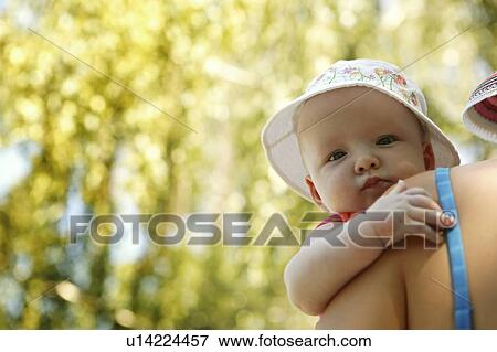 Stock Photo - Infant wearing sun hat is carried by mother, Echo Lake, Saskatchewan, Canada. Fotosearch