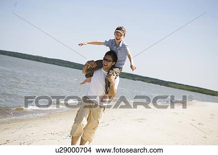 Picture - Man carries boy (7) on his shoulders, Grand Beach Provincial Park, Manitoba, Canada. Fotosearch