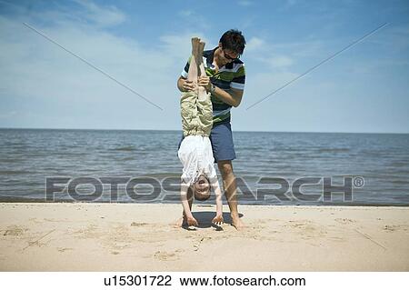 Man holds boy upside down, Grand Beach Provincial Park, Manitoba, Canada View Large Photo Image Stock Image - Man holds boy upside down, Grand Beach Provincial Park, Manitoba, Canada. Fotosearch