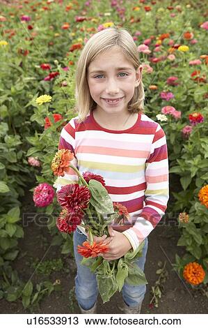 Stock Image - Nine year old girl in field of flowers holding a bundle of flowers, Ladner, British Columbia, Canada. Fotosearch