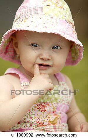 Stock Image - Toddler wearing sunhat with finger in mouth, Saskatchewan, Canada. Fotosearch