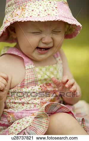 Stock Image - Toddler wearing sunhat with sneezing expression, Saskatchewan, Cnada. Fotosearch