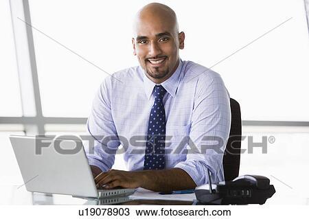 Businessman in office with laptop smiling (high key/selective focus) View Large Photo Image Stock Image - Businessman in office with laptop smiling (high key/selective focus). Fotosearch