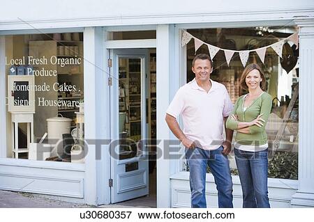 Stock Photo - Couple standing in front of organic food store smiling. Fotosearch