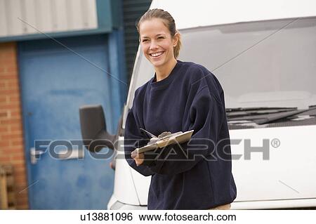 Deliveryperson standing with van writing in clipboard smiling View Large Photo Image Stock Photograph - Deliveryperson standing with van writing in clipboard smiling. Fotosearch