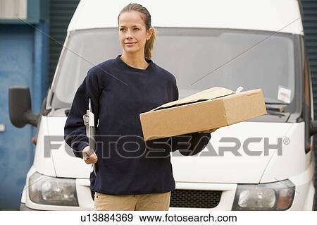 Stock Photo - Deliveryperson standing with van with clipboard and box. Fotosearch
