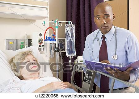 Doctor Making Notes About Patient, Looking Serious View Large Photo Image Stock Photograph - Doctor Making Notes About Patient, Looking Serious. Fotosearch