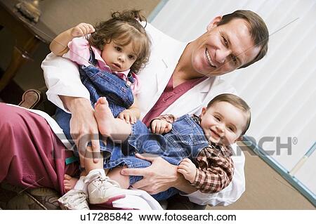 Doctor sitting with two IVF children smiling View Large Photo Image Stock Image - Doctor sitting with two IVF children smiling. Fotosearch