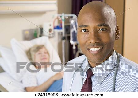 Stock Photograph - Doctor Smiling, Standing In Hospital Room. Fotosearch