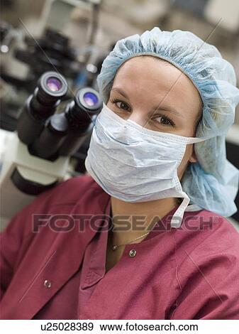 Embryologist sitting by microscope with mask on (selective focus) View Large Photo Image Stock Photo - Embryologist sitting by microscope with mask on (selective focus). Fotosearch