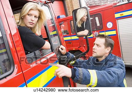 Fireman pointing something out to firewoman sitting in fire engine View Large Photo Image Stock Image - Fireman pointing something out to firewoman sitting in fire engine. Fotosearch