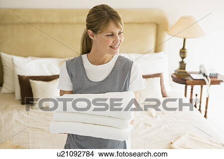 Picture - Maid holding towels in hotel room smiling. Fotosearch