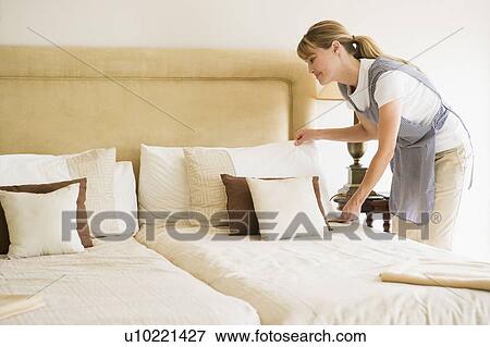 Maid making bed in hotel room smiling View Large Photo Image Stock Photo - Maid making bed in hotel room smiling. Fotosearch