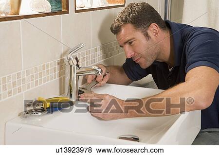 Stock Photo - Plumber working on sink. Fotosearch