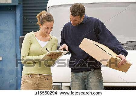Two deliverypeople standing with van holding clipboard and box View Large Photo Image Picture - Two deliverypeople standing with van holding clipboard and box. Fotosearch