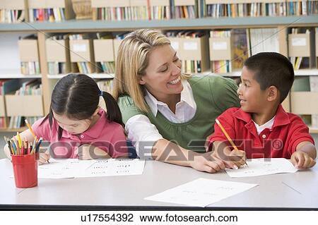 Two students in class writing with teacher helping View Large Photo Image Stock Image - Two students in class writing with teacher helping. Fotosearch