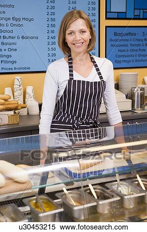 Stock Photography - Woman standing at counter in restaurant smiling. Fotosearch