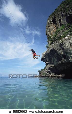 Couple outdoors jumping off cliff into ocean View Large Photo Image Stock Image - Couple outdoors jumping off cliff into ocean. Fotosearch