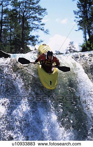 Stock Image - Kayaker in rapids going over waterfall (selective focus). Fotosearch