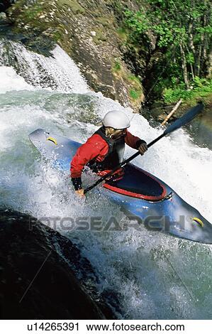 Stock Image - Kayaker in rapids going over waterfall (blur). Fotosearch