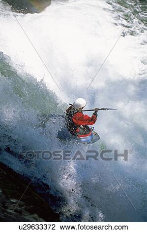 Stock Image - Kayaker in rapids going over waterfall. Fotosearch