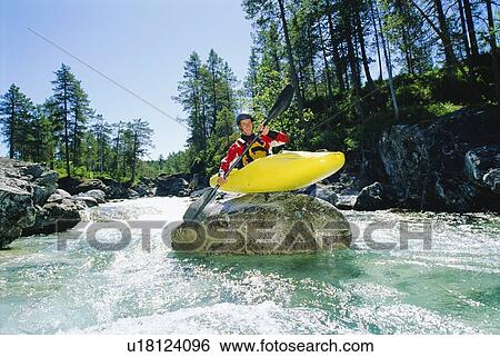 Stock Photograph - Kayaker on top of rock in rapids smiling. Fotosearch