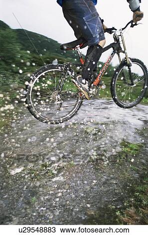 Man outdoors on trails jumping bicycle over puddles (selective focus) View Large Photo Image Stock Image - Man outdoors on trails jumping bicycle over puddles (selective focus). Fotosearch
