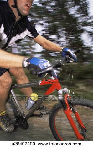 Stock Image - Man outdoors on trails riding bicycle (out of focus). Fotosearch