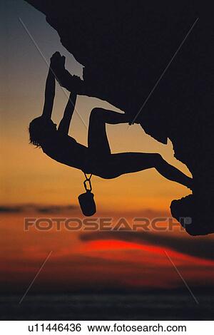 Stock Photograph - Mountain climber coming up under mountain cliff (silhouette). Fotosearch