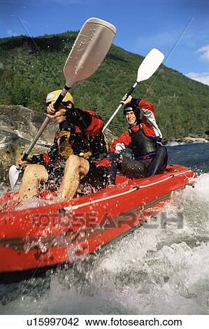 Stock Image - Two kayakers going into in rapids and smiling (selective focus). Fotosearch