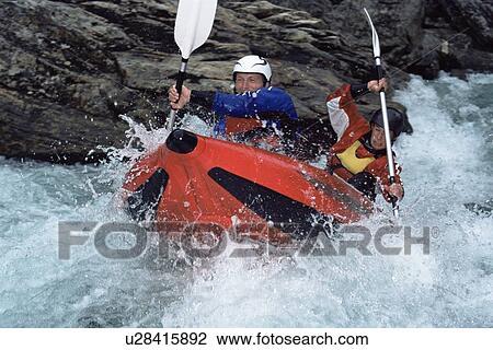 Stock Image - Two kayakers rowing in rapids. Fotosearch
