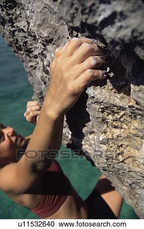 Woman climbing rocks in swimwear by ocean (selective focus) View Large Photo Image Stock Image - Woman climbing rocks in swimwear by ocean (selective focus). Fotosearch