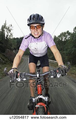 Woman outdoors on trails riding bicycle and smiling (selective focus) View Large Photo Image Stock Photo - Woman outdoors on trails riding bicycle and smiling (selective focus). Fotosearch