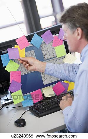 Businessman in office at monitor with notes on it View Large Photo Image Stock Photography - Businessman in office at monitor with notes on it. Fotosearch